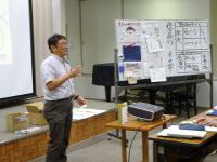 ホワイトボードで立体リーフレットの説明をする講師